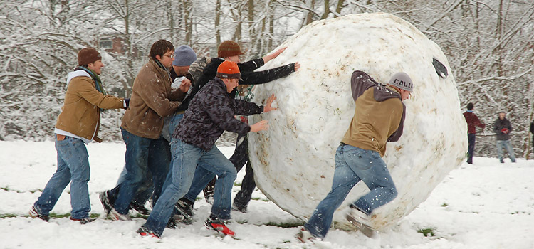 People pushing a giant snowball